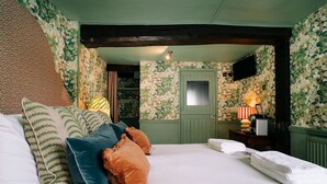 Un dormitorio con cama, almohadas, cómoda, espejo y radiador.