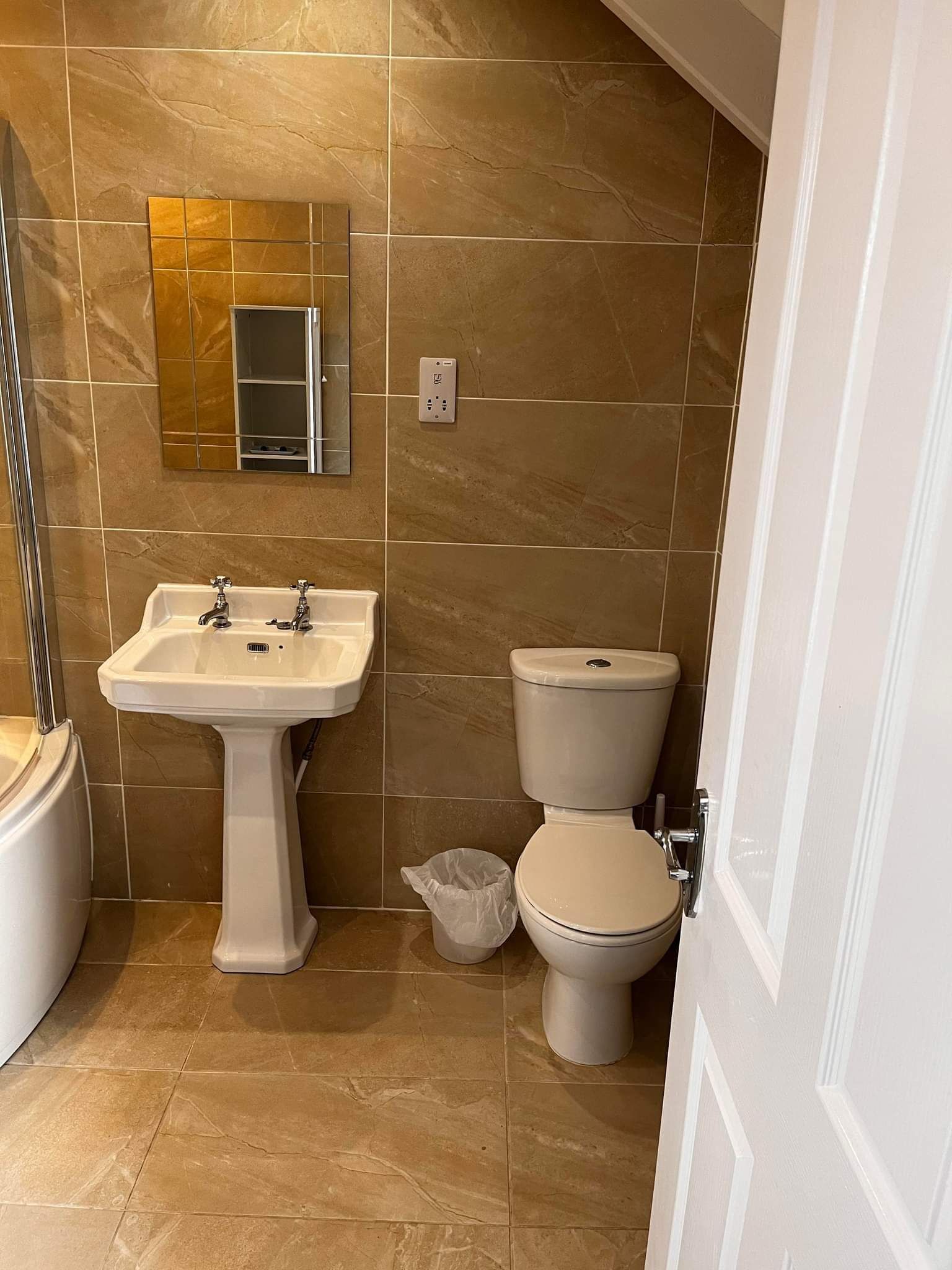 Ein Badezimmer mit einem Standwaschbecken, einer Toilette und einem Spiegel über dem Waschbecken.