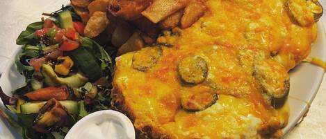 A plate with a grilled cheese sandwich, fries, and a side salad with a small container of sauce.