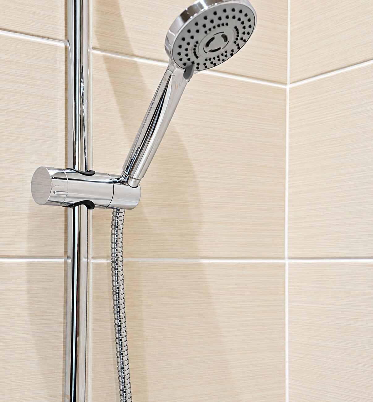A showerhead with a flexible hose, mounted on a chrome fixture.