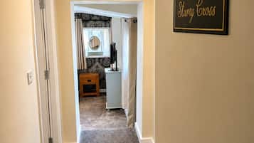 A hallway leading to a bathroom with a vanity, a towel rack, and a sign that reads 'Sturdy Cross'.