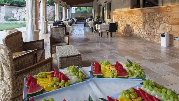 Un espace extérieur aménagé pour les repas, avec des meubles en osier et une variété d’assiettes de fruits.
