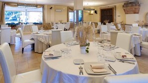 Un espace repas avec des tables rondes disposées pour accueillir quatre personnes, des chaises blanches et un vase décoratif placé au centre.