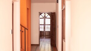 A hallway with a tiled floor leading to a wooden door with glass panels. - Donna Alda Casa (Salta)