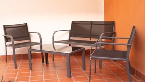 A corner seating area with a metal table and chairs, a tiled floor, and an orange wall. - Donna Alda Casa (Salta)