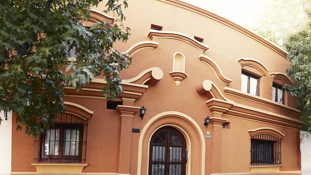 A building with a curved facade, large arched entrance, and multiple windows with decorative ironwork. - Donna Alda Casa (Salta)