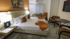 A hotel room with a bed, a desk, a chair, a small table, and a TV. - Hotel Aromax del Campestre (Medellín)