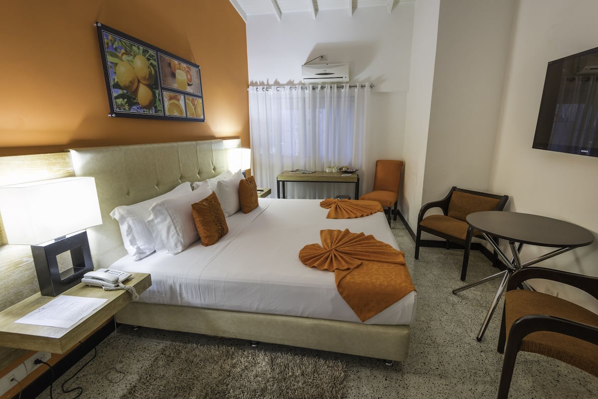 Ein Hotelzimmer mit Bett, Schreibtisch, Stuhl, kleinem Tisch und Fernseher.