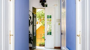 A hallway with blue walls, a patterned rug, and a door leading to a room with a view of greenery. - Villa Alicia Guest House (Málaga)