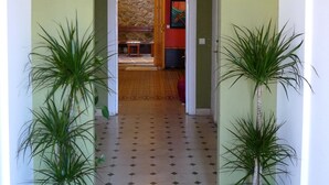 A hallway with a tiled floor, two potted plants on either side, an arched doorway, and a hanging light fixture. - Villa Alicia Guest House (Málaga)