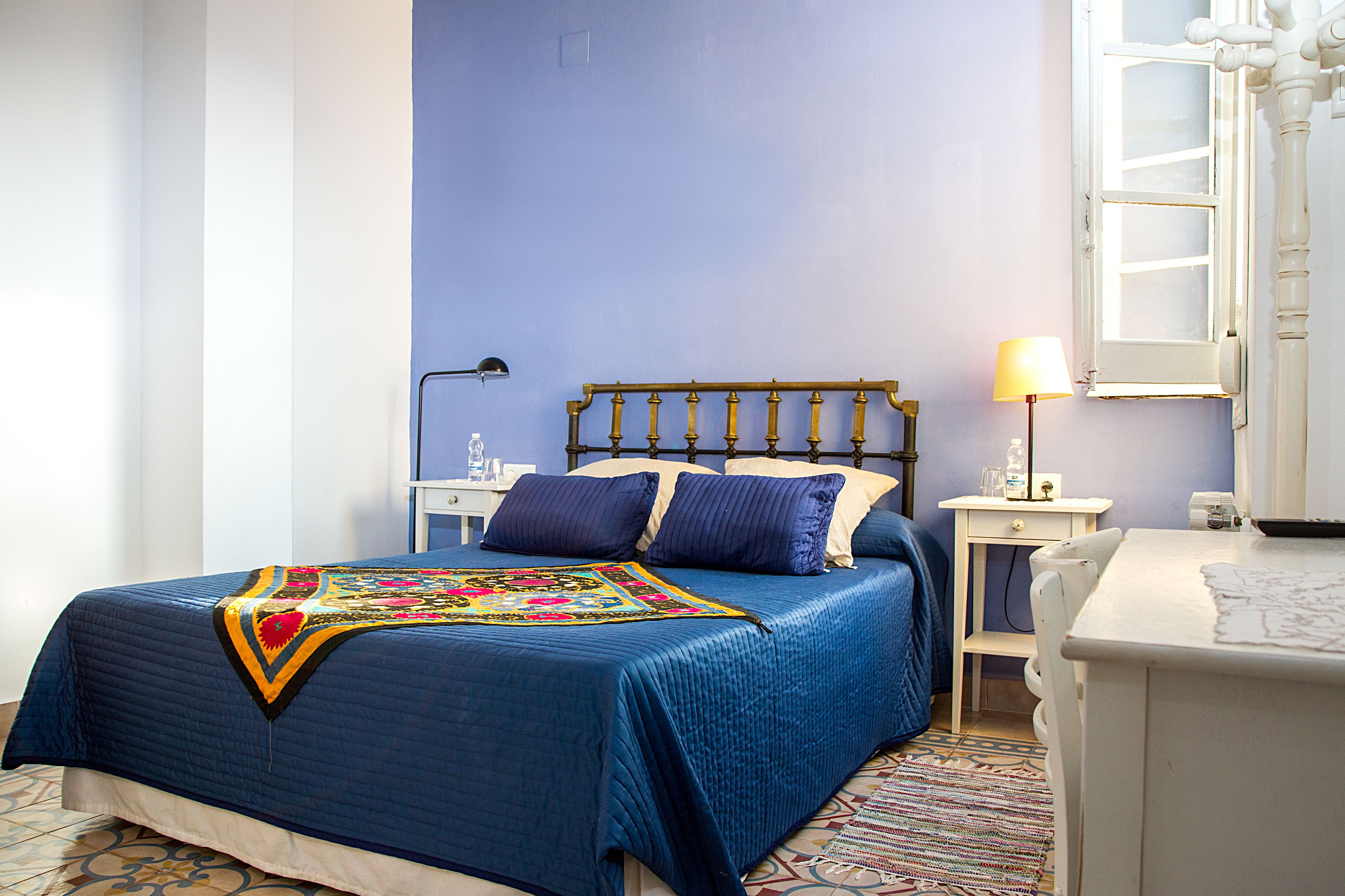 Een slaapkamer met een bed, nachtkastjes, een lamp en een raam.