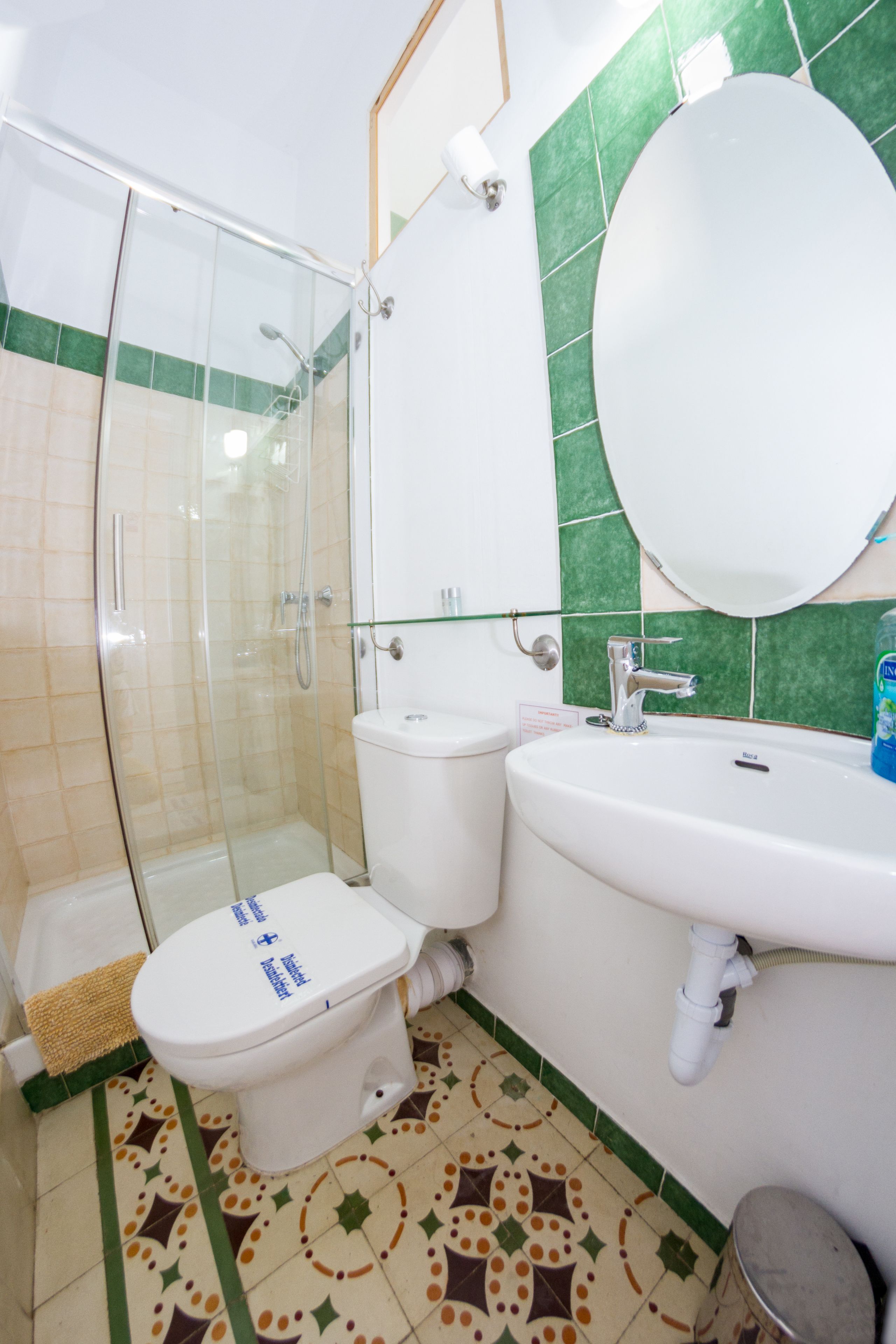 Ein Badezimmer mit einer Duschkabine, einer Toilette, einem Waschbecken und einem Spiegel.