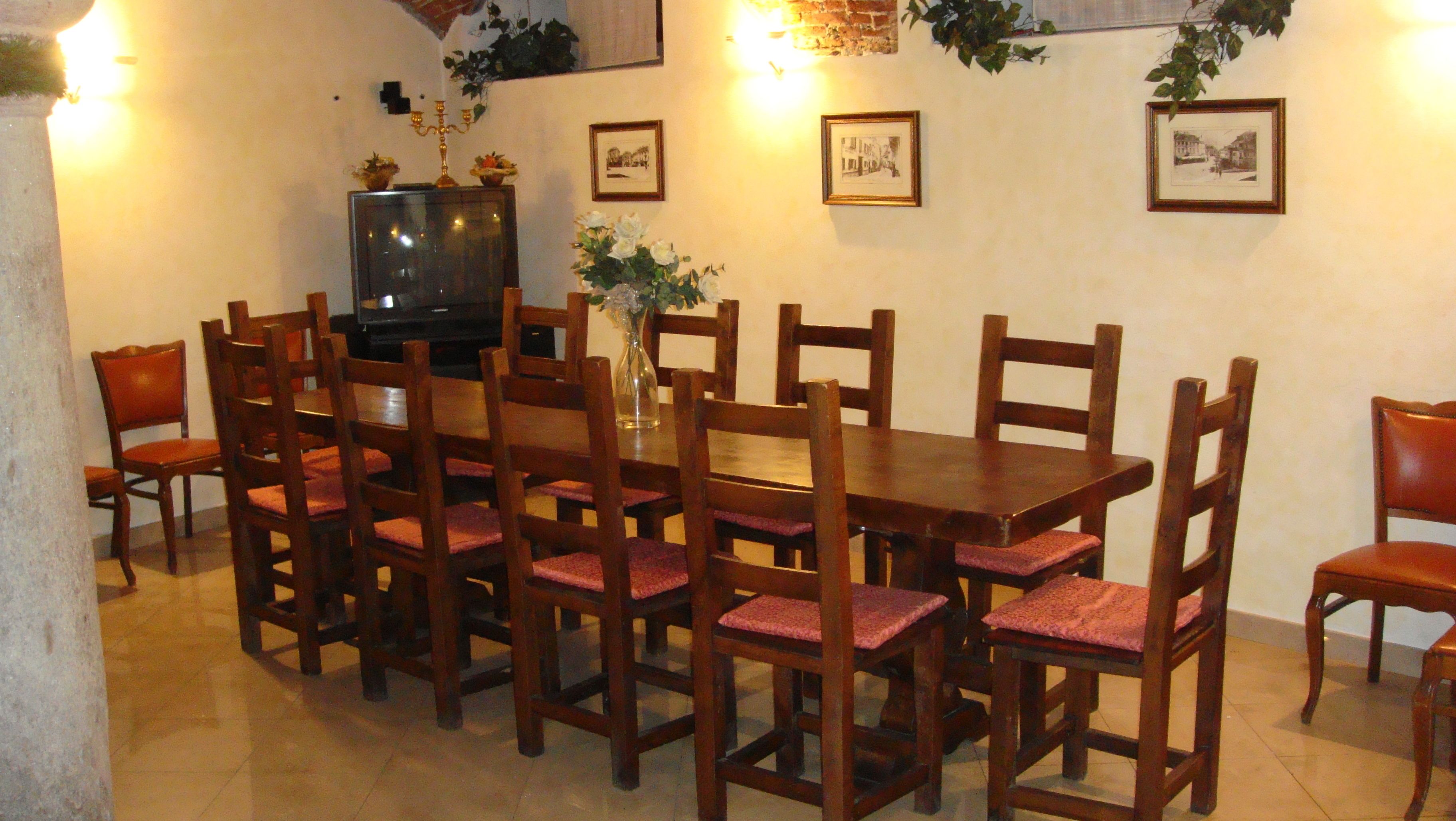 A dining area with a wooden table and chairs, a television, and framed pictures on the wall.