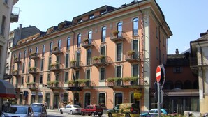 Een meerlaags gebouw met balkons, een restaurant/hotelbord en geparkeerde auto's.