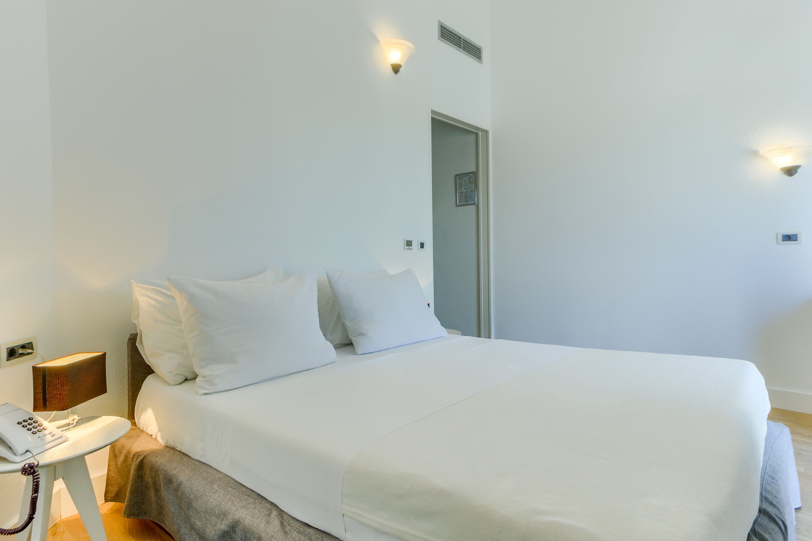 Una habitación de hotel con una cama individual, una mesita de noche con lámpara y un teléfono.