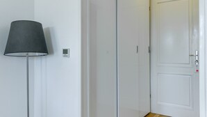 Un pasillo con una lámpara de pie, un termostato y una puerta con cerradura y botón de pánico.