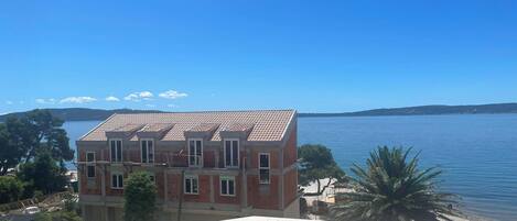 A building with a tiled roof, a balcony, and a view of a large body of water.