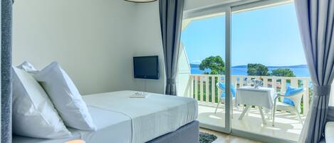 A modern bedroom with a bed, a TV, and a balcony with a table and chairs.