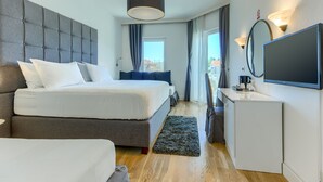 Una habitación de hotel moderna con una cama grande, una mesita de noche, un televisor de pantalla plana y vistas a la ciudad desde la ventana.