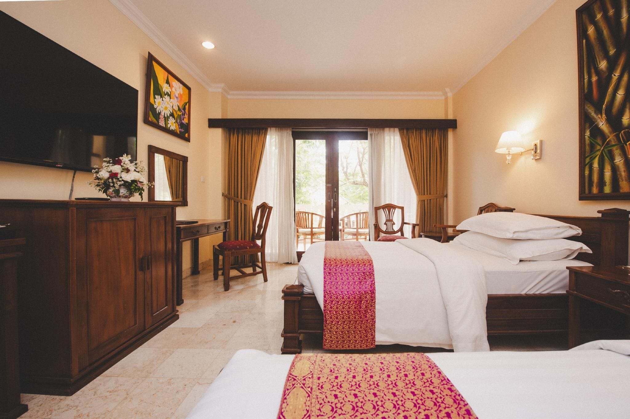 A hotel room with a bed, a desk, a television, and a window with curtains.