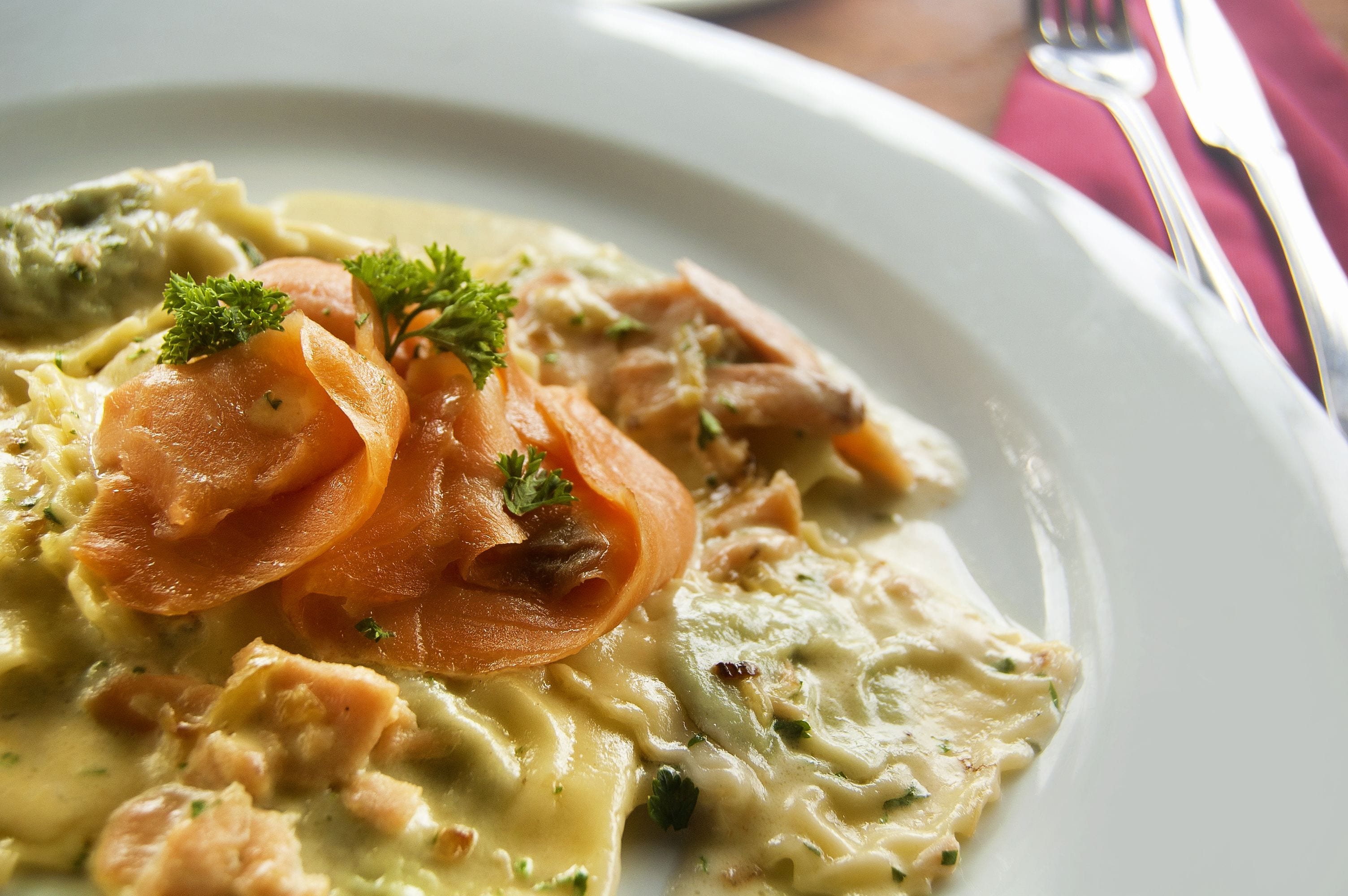 A plate of food with salmon, carrots, and a creamy sauce, garnished with parsley.