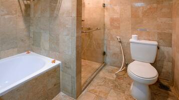 Un baño con bañera, inodoro y ducha con mampara de vidrio.