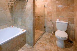 Un baño con bañera, inodoro y ducha con mampara de vidrio.