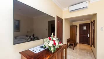 Una recepción con un espejo, un arreglo floral y un banco de madera.