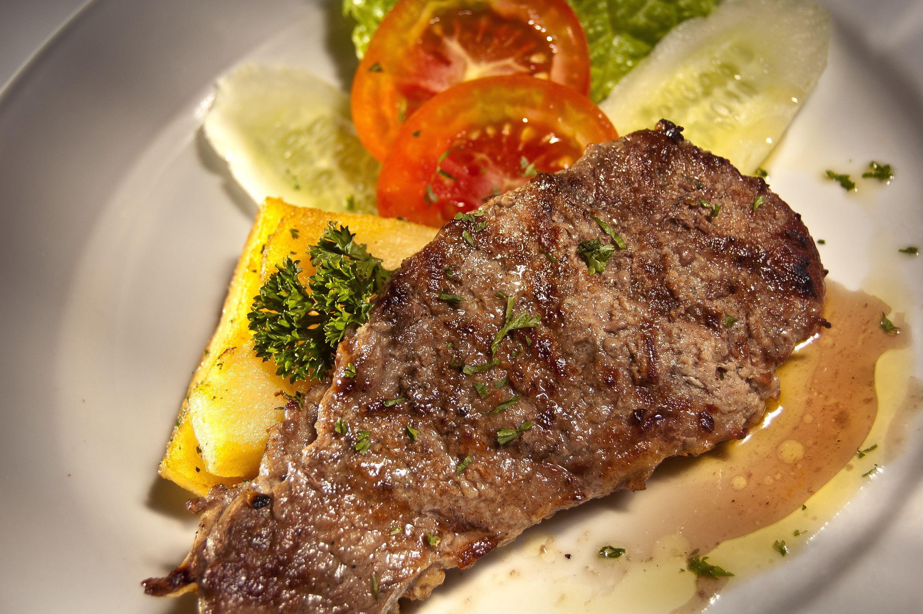 A plate with a grilled steak, lemon slices, and a garnish of parsley.