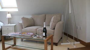 Un salon avec une table basse en verre, un canapé beige, un lampadaire et une lampe sur pied.