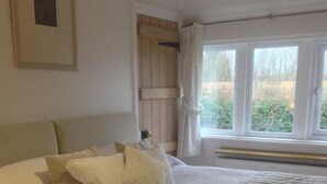 Une chambre avec un grand lit, une porte en bois et une fenêtre avec des rideaux.