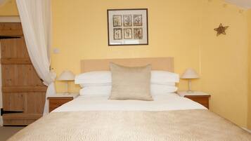 A bedroom with a bed, two bedside tables, a nightstand, a wooden wardrobe, and a wall-mounted picture.