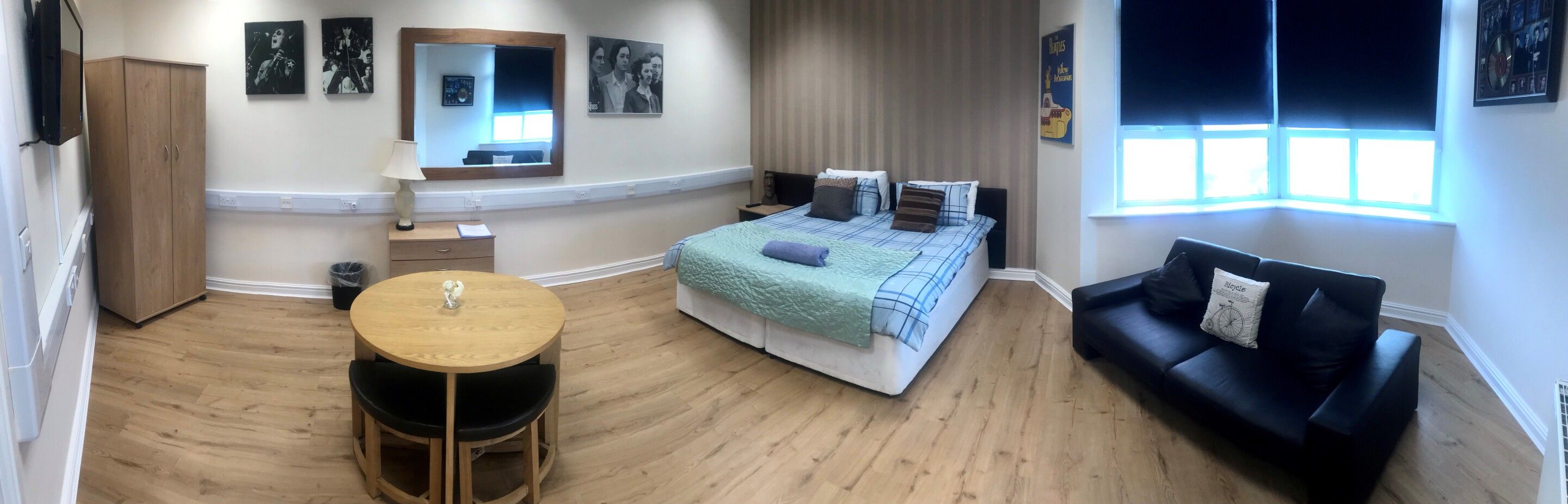 A room with a bed, a round table, a sofa, and a wardrobe.