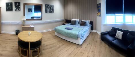 A room with a bed, a round table, a sofa, and a wardrobe.
