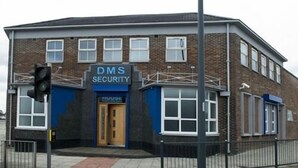 Een gebouw met een bord waarop 'DMS SECURITY' staat en een deur met de tekst 'HOUSE'.