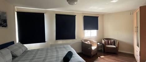 Une chambre à coucher avec un lit, deux chaises, un radiateur et une armoire.
