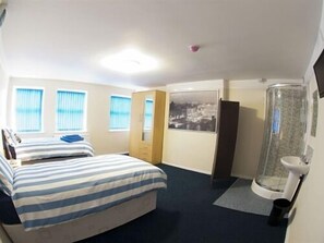 A hotel room with two beds, a shower, a toilet, and a window with blinds. - Liverpool Gateway Inn (Liverpool)