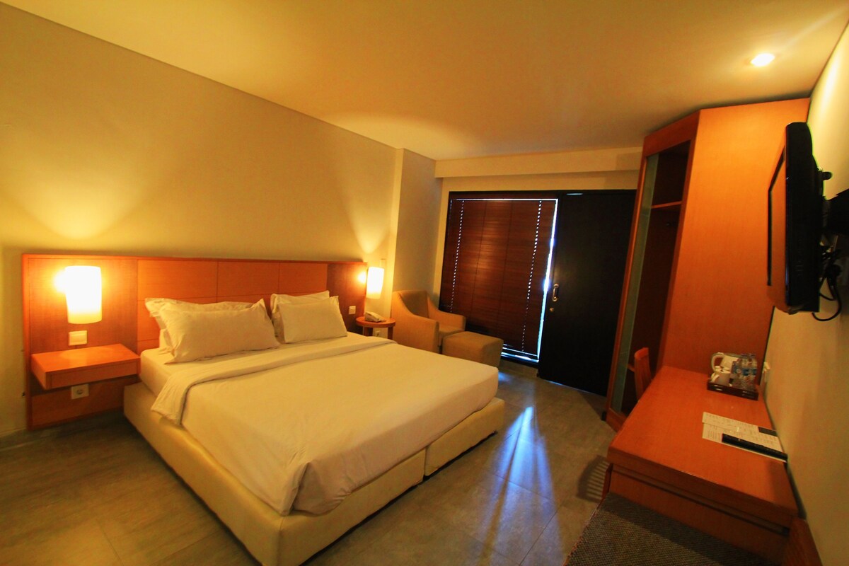 A hotel room with a large bed, bedside tables, a desk, and a chair.
