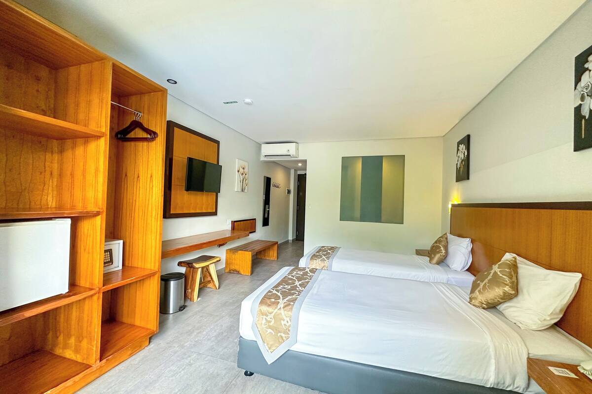 A hotel room with a large bed, wooden shelving, a flat-screen TV, and a small seating area.