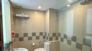 A modern bathroom with a glass shower enclosure, a sink, and a toilet. - Dekuta Hotel (Kuta)