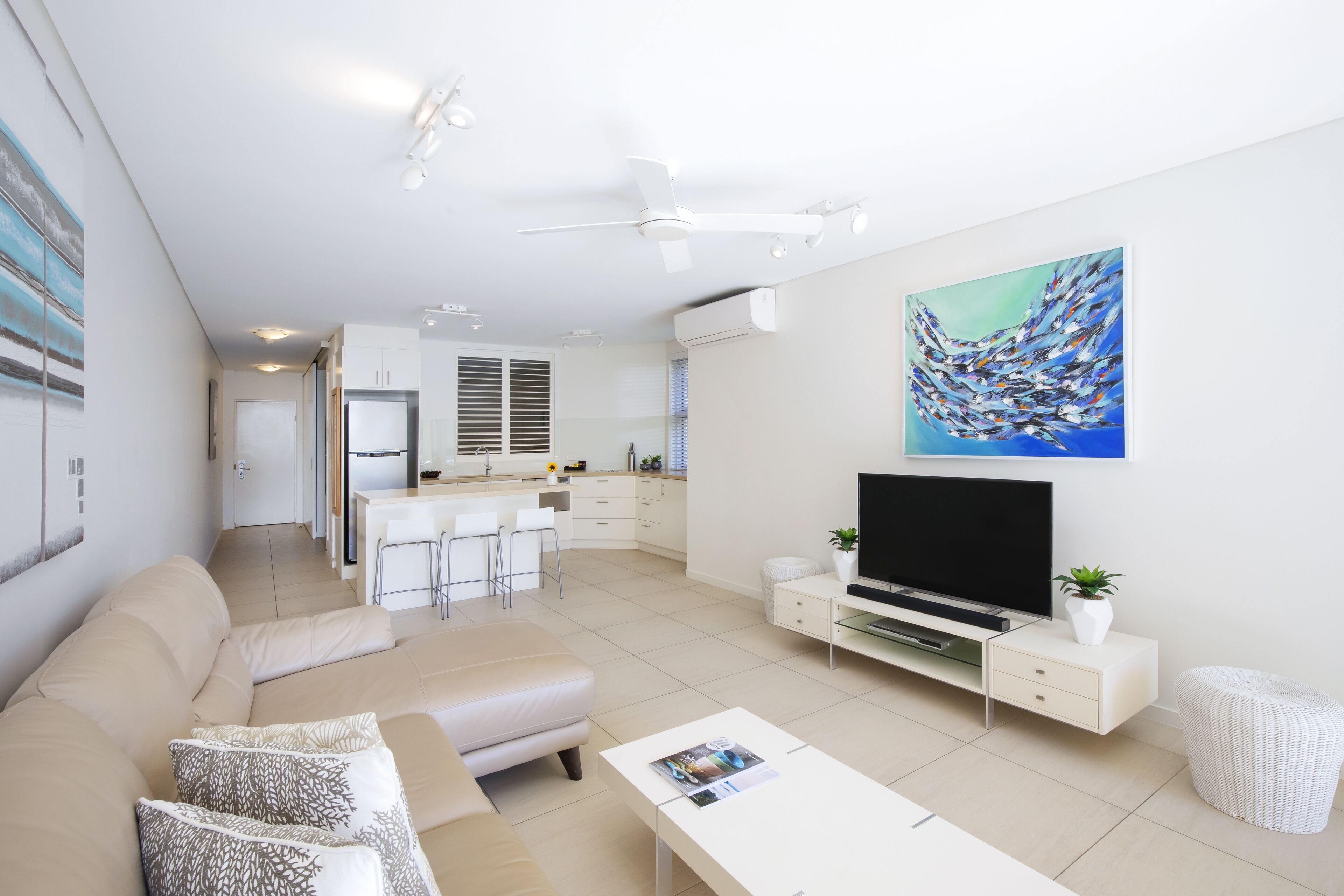 Una sala de estar moderna con sofá, televisión y obras de arte.