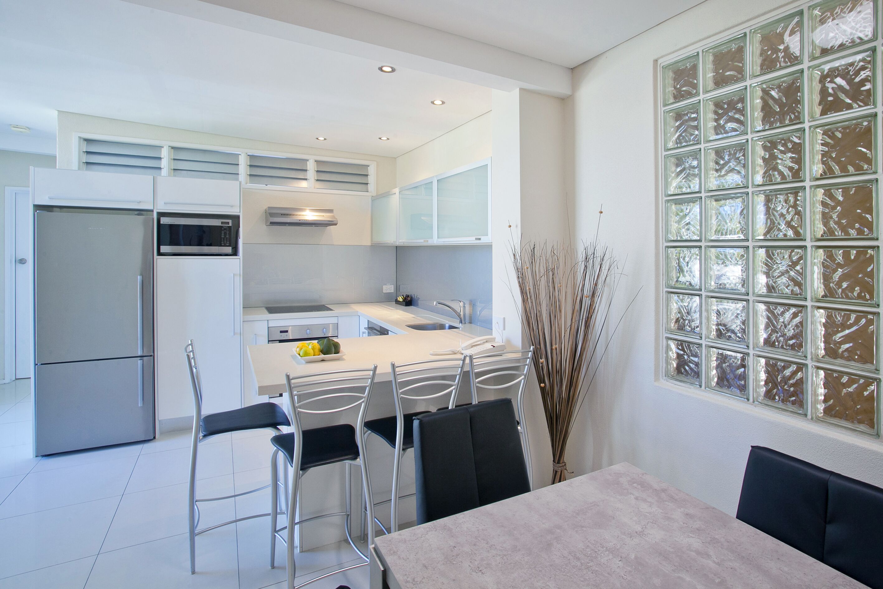 A modern kitchen with stainless steel appliances, a central island, and a dining area with a table and chairs.