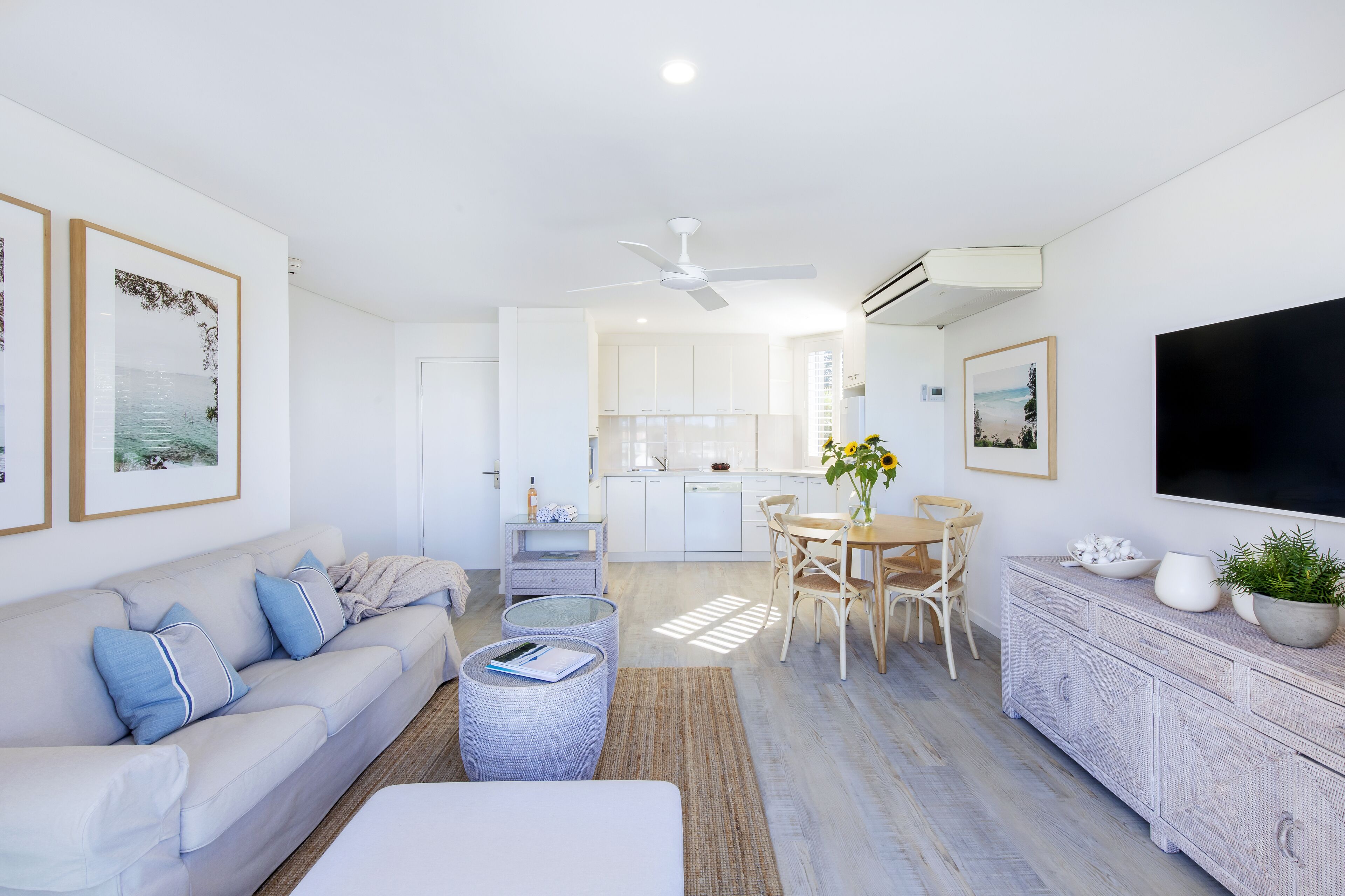 A modern living room with a sofa, coffee table, and a dining area with chairs and a table.