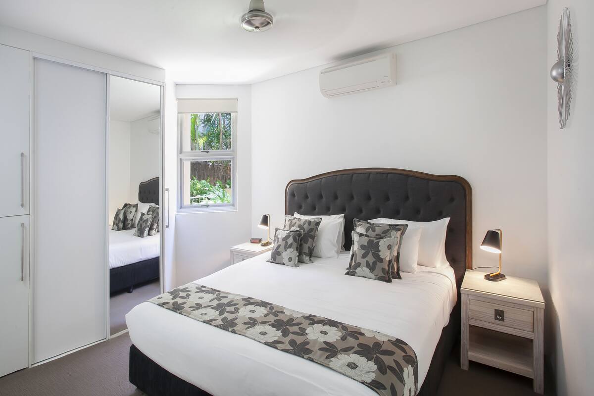 Une chambre à coucher avec un lit, des tables de chevet, une armoire et une fenêtre.