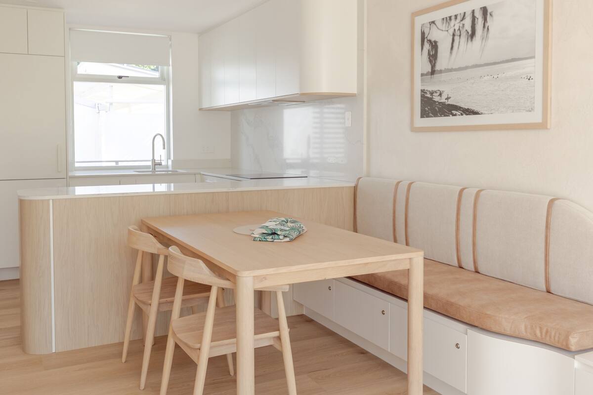 Une cuisine moderne avec une table et des chaises en bois, un banc intégré et une grande fenêtre.