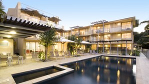 Ein modernes Hotel mit Schwimmbad, Außenbereich zum Sitzen und mehreren Balkonen.