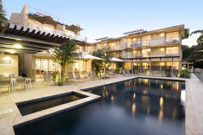 Una piscina al aire libre, sombrillas, tumbonas