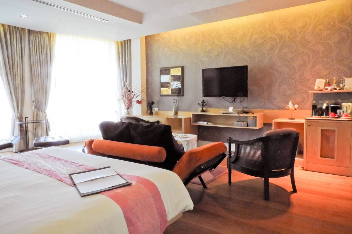 Ein Hotelzimmer mit Bett, Schreibtisch, Stuhl, Fernseher und Minibar.
