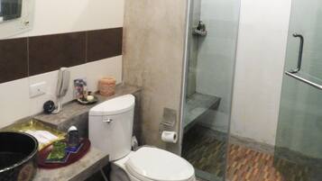 A bathroom with a toilet, a shower, and a sink.