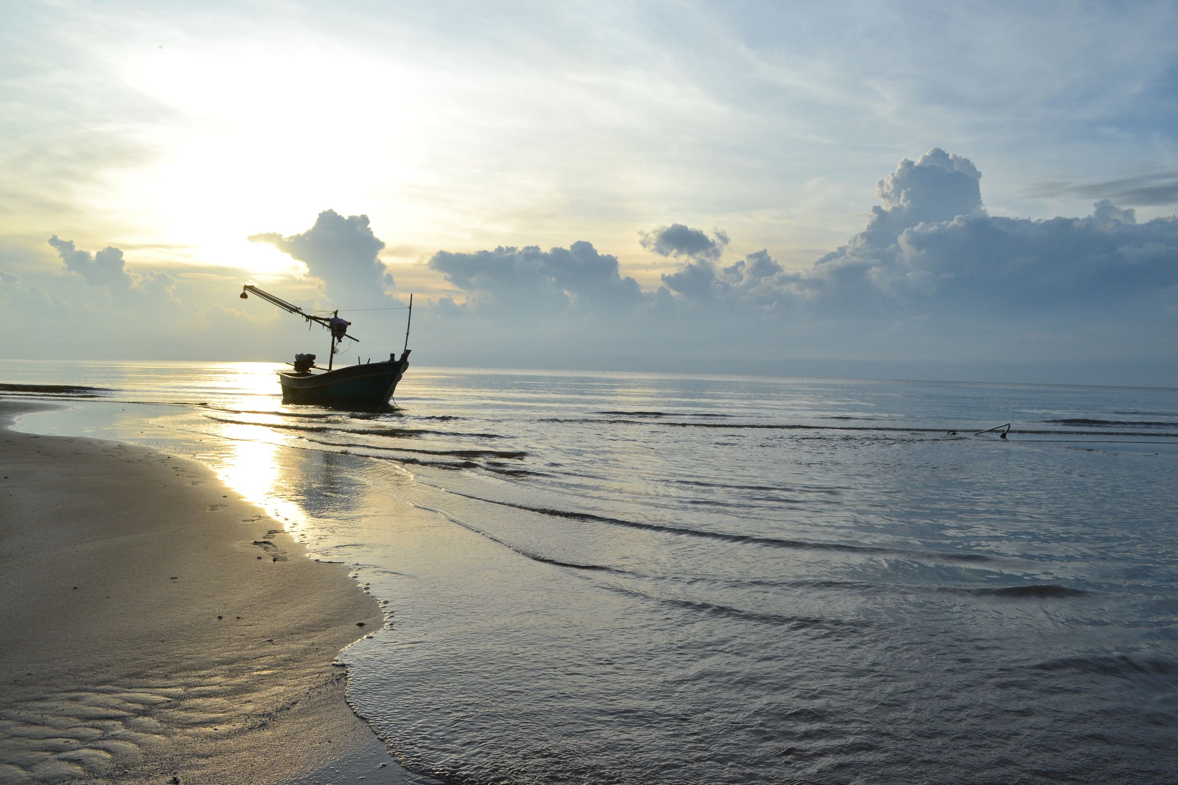 A boat on a beach with a sunset in the background.